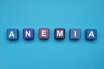 Obraz premium Wooden cubes with word Anemia on light blue background, flat lay