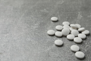 Fototapeta na wymiar Pile of calcium supplement pills on grey table, space for text