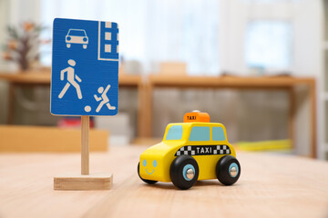 Fototapeta Miniature road sign and car on wooden table, closeup. Montessori toy obraz