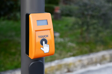 Orange traffic light push button on pillar outdoors