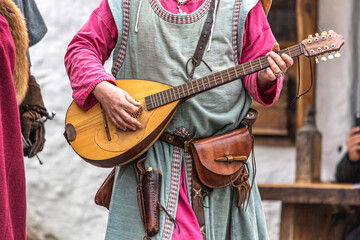 Close-up of medieval larp cosplay costumes, an unrecognizable person holding a medieval guitar