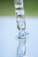Pipette with transparent liquid against blue and green background with copy space. Texture of face...