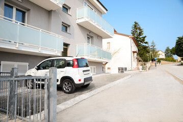 Fototapeta Apartment building and parked car on sunny day obraz