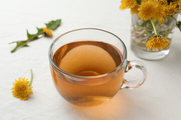 Delicious fresh tea and beautiful dandelion flowers on white table
