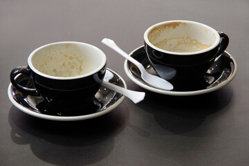 Two black and white empty coffee cappuccino cups and saucers
