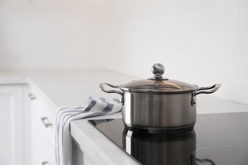 New clean pot on cooktop in kitchen, space for text - obrazy, fototapety, plakaty