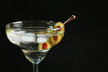 Martini cocktail with ice and olives on dark background, closeup. Space for text
