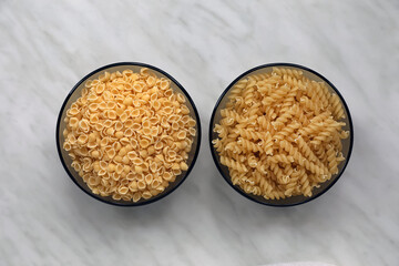Different types of pasta on white marble table, flat lay