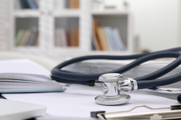 Book, stethoscope and clipboard indoors, closeup with space for text. Medical education