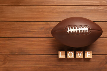 American football ball and cubes with word Love on wooden background, flat lay. Space for text
