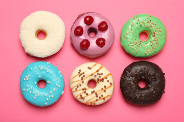 Different delicious glazed doughnuts on pink background, flat lay