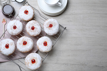 Many delicious donuts with jelly and powdered sugar on wooden table, flat lay. Space for text