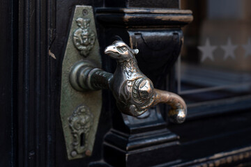 Old door handle. Wooden vintage entrance door with antique door handles in the shape of bird. Selective focus