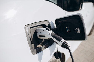Close up of a electric car charger with female silhouette in the background, entering the home door...
