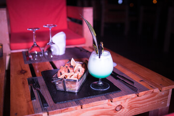 Small portion of onion rings with a cold cocktail drink beside it