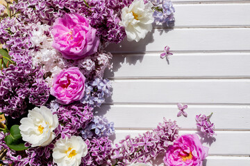 blossom Syringa vulgaris in Lilac flower space for text message.Top view. Romantic flowers composition. Mock up frame with blooming buds of pink roses, lilac flowers on white background.floral layout