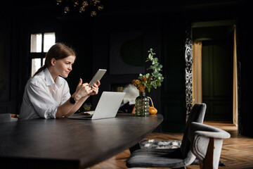 The female receptionist at the hotel hostel uses a laptop to communicate with guests. Freelancer work surfing the Internet on a device.