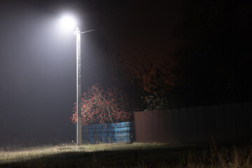 Poles with street lamps at night in fog in the village, Russia