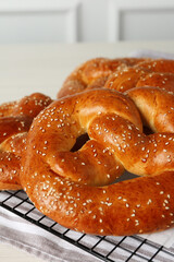 Tasty freshly baked pretzels on cooling grid, closeup view