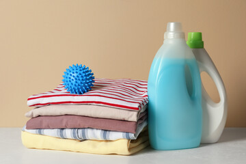 Obraz na płótnie Canvas Blue dryer ball and stacked clean clothes near laundry detergents on white table