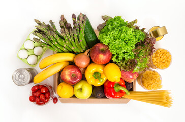 Donation box with fresh fruit and vegetables, eggs, pasta and canned food. Food delivery and shopping concept. Vegetarian grocery products, isolated on white background. Top view.