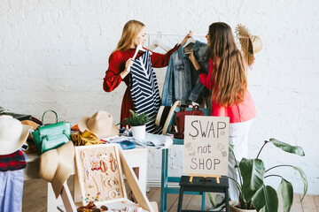 two young woman female caucasian students at swap party try on clothes, bags, shoes and...