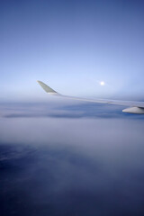 Moon, clouds and the airplane wing, view from the passenger's window.