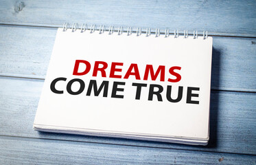 Dreams Come True text on notebook on wooden table