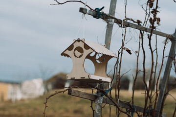 Wooden bird feeder in nature with a blurred background. Feeding birds after winter. House for birds.