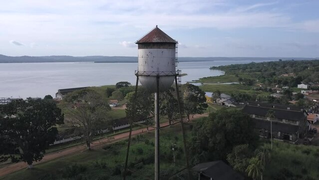 Drone aerial view of Fordlandia city skyline in Amazon rainforest, Brazil. Tapajos river and historic water tank tower. Town built by Henry Ford in 1928 to produce rubber in the middle of the forest.