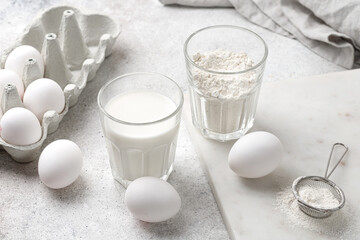 Dairy product, Glass of milk, glass of flour, eggs on grey background. Baking cake ingredients. White on white