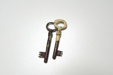 Two antique keys on a white table.
