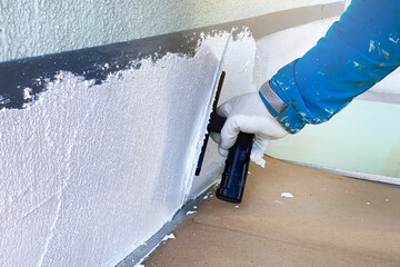 The builder applies a fresh texture to the facade of the house. Large spatula in the hands of a...