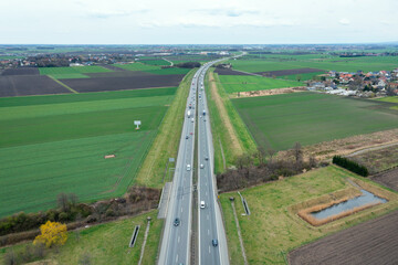 A lot of trucks on the highway among the green fields, view from above.