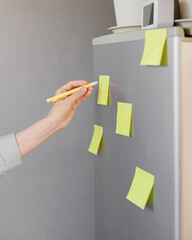 a woman makes notes on colored stickers on the refrigerator. a reminder or a note for her husband...