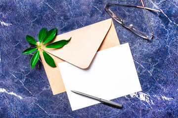 On a dark marble background, an open envelope, glasses, a pen, a sheet of paper with a place to...