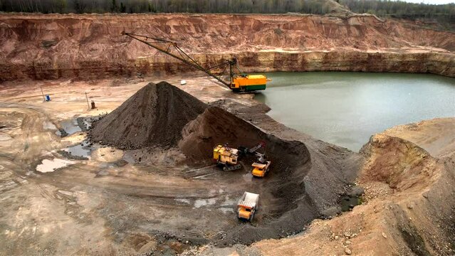 Mining excavator loading dolomite minerals in haul truck. Limestone mining in a dolomite quarry. Walking dragline excavator in an open pit. Mining truck transports limestone from opecast, drone view.