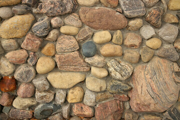 Close up of A stone Wall Built with Multi Colored Rocks and Cement Mortar. Background texture