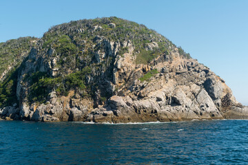 Fototapeta na wymiar Montanha rochosa a beira do mar e lindo céu azul, localizada na região de Cabo Frio, Rio de Janeiro, Brasil.