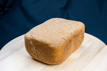 The freshly baked bread on a wooden board and black background close-up. Making bread. Top view.