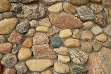 Close up of A stone Wall Built with Multi Colored Rocks and Cement Mortar. Background texture
