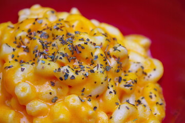 Macaroni cheese served in orange cup plates with Oregano garnish.