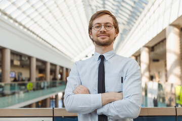 Portrait of handsome cheerful intelligent man in glasses over modern building background