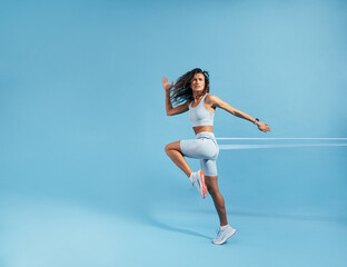 Woman exercising with resistance band on blue background. Caucasian female athlete working out with elastic bands.