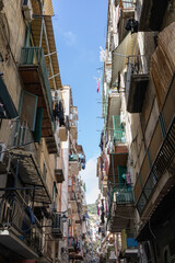 Fototapeta na wymiar 9 april 2022, Naples, Italy. A walk in the picturesque narrow alleys of the Spanish Neighborhood (Quartieri Spagnoli), the heart and soul of Naples, looking up at the sky.