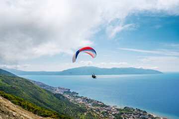 Athlete paragliding against the backdrop of a cloudy sky over the mountains on a summer day.