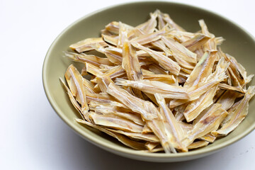 Dried anchovies in bowl on white background.