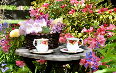 Spring garden afternoon tea with lilacs and tulip bouquet in beautiful garden setting - obrazy, fototapety, plakaty