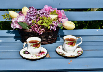 Spring garden afternoon tea with lilacs and tulip bouquet in beautiful garden setting