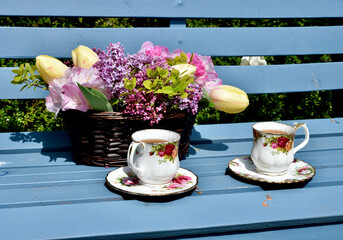 Spring garden afternoon tea with lilacs and tulip bouquet in beautiful garden setting